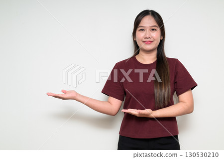 Studio portrait of young Asian woman presenting something against white background Studio portrait of young Asian woman presenting something against white background 130530210