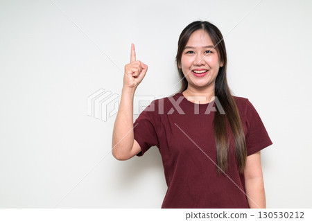 Studio portrait of young Asian woman pointing finger up against white background 130530212