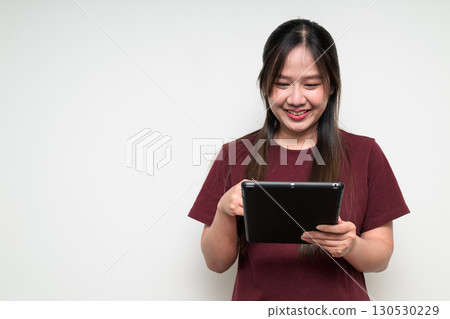 Studio portrait of happy young Asian woman using digital tablet computer against white background Studio portrait of happy young Asian woman using digital tablet computer against white background 130530229