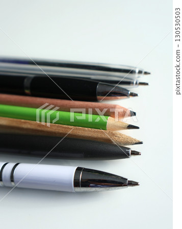 Assorted Pens and Pencils Arranged on Light Background Assorted Pens and Pencils Arranged on Light Background 130530503