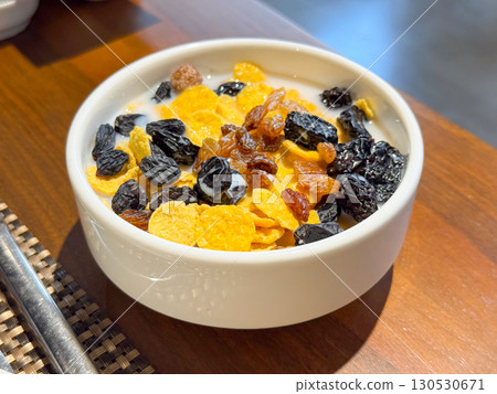 Bowl with cornflakes, raisins, and milk served for breakfast. Nutrition, daily habit, and food culture in lifestyle environment. Bowl with cornflakes, raisins, and milk served for breakfast. Nutrition, daily habit, and food culture in lifestyle environment. 130530671