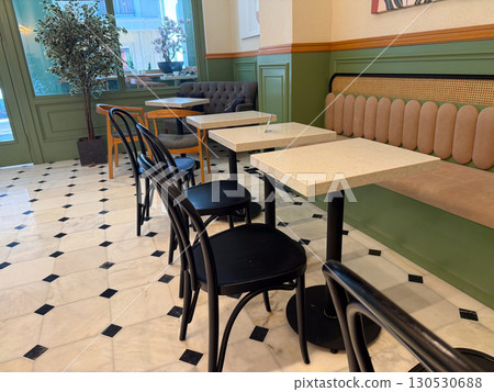 Empty cafe interior with tables, chairs, tiled floor, and green walls. Hospitality, modern design, and daily lifestyle in comfortable social environment. 130530688