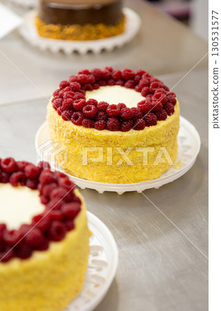 Decorated raspberry cake with cream and crumbs on metal table in pastry kitchen Decorated raspberry cake with cream and crumbs on metal table in pastry kitchen 130531577