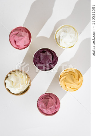 Assorted colorful soft serve ice cream in paper cups on white background, top view Assorted colorful soft serve ice cream in paper cups on white background, top view 130531595
