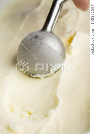 Vanilla ice cream scoop in metal spoon over creamy background, macro food texture shot Vanilla ice cream scoop in metal spoon over creamy background, macro food texture shot 130531597