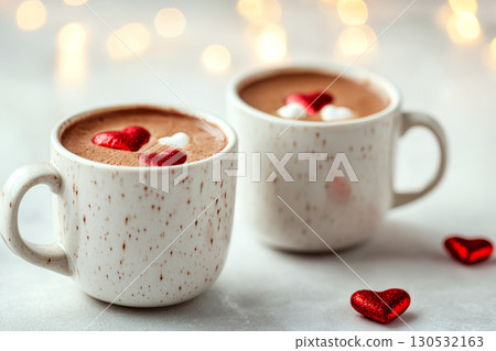 Two white mugs filled with hot chocolate topped with red and white heart-shaped decorations. Concept of warmth and romance. For Valentine's Day greeting. 130532163
