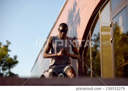 Athletic man exercising outdoors against a modern building facade Athletic man exercising outdoors against a modern building facade 130532279