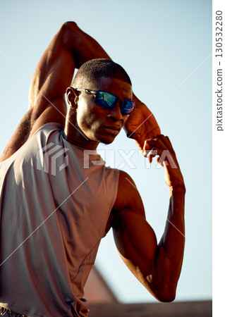 Man Stretching Outdoors in Sunglasses During a Workout Session Man Stretching Outdoors in Sunglasses During a Workout Session 130532280