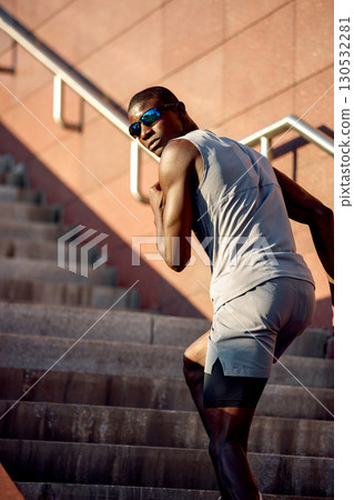 Athletic man jogging up stairs in outdoor urban environment on a sunny day Athletic man jogging up stairs in outdoor urban environment on a sunny day 130532281