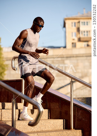 Athletic man running on outdoor stairs during sunny day 130532282