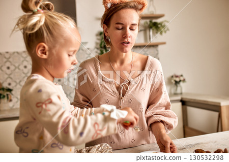 Mother and daughter enjoying baking together in a cozy modern kitchen setting 130532298