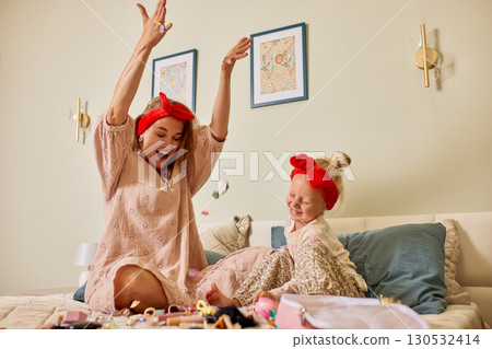 Mother and daughter enjoying playful moments together with colorful toys on a bed 130532414