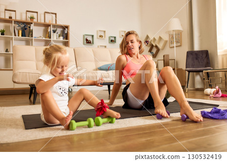 Mother and daughter exercising together at home, promoting health and bonding Mother and daughter exercising together at home, promoting health and bonding 130532419