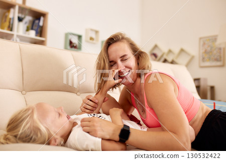 Mother and child enjoying playful bonding time on a cozy home sofa Mother and child enjoying playful bonding time on a cozy home sofa 130532422