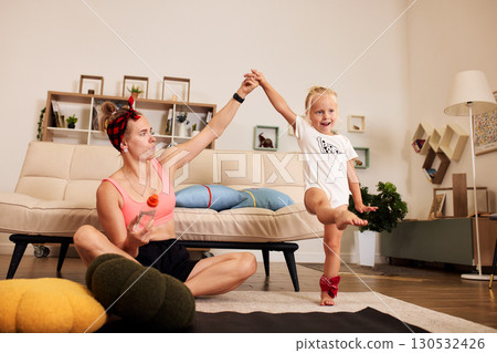 Mother and daughter exercising happily together in a cozy modern living room 130532426