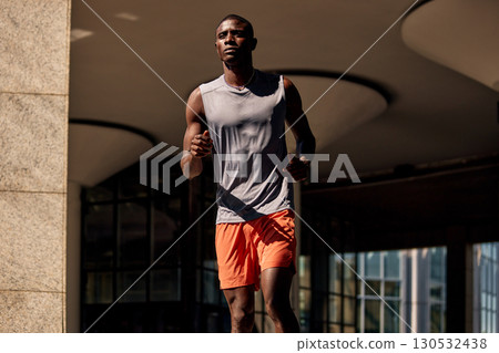 Athletic man jogging outdoors wearing bright sportswear under urban architecture lighting Athletic man jogging outdoors wearing bright sportswear under urban architecture lighting 130532438