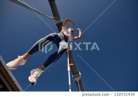 Dynamic perspective of an active woman on a bridge under a clear sky 130532439