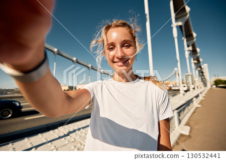 Young woman smiling during a sunny day on a city bridge Young woman smiling during a sunny day on a city bridge 130532441
