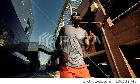 Athletic man running outdoors against the backdrop of modern urban architecture 130532445
