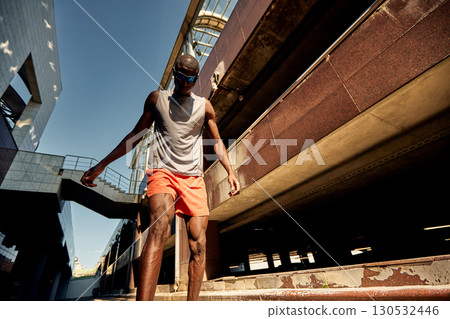 Athletic man outdoors wearing vibrant attire near urban architecture in summer light Athletic man outdoors wearing vibrant attire near urban architecture in summer light 130532446
