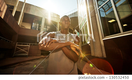 Young man stretching outdoors with urban backdrop on a sunny day 130532450