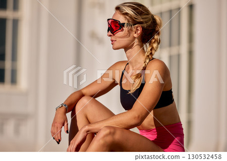 Woman in sportswear resting outdoors with dynamic pose and sunny background Woman in sportswear resting outdoors with dynamic pose and sunny background 130532458