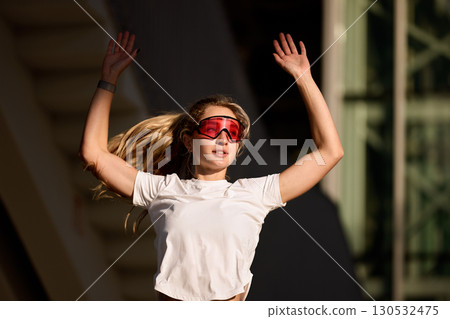 Athletic woman with raised arms exercising outdoors in sportswear Athletic woman with raised arms exercising outdoors in sportswear 130532475