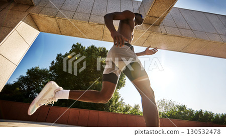 Athletic man running outdoors under a modern structure on a sunny day 130532478
