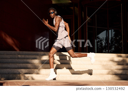 Athletic man sprinting outdoors on urban staircase during sunny day Athletic man sprinting outdoors on urban staircase during sunny day 130532492