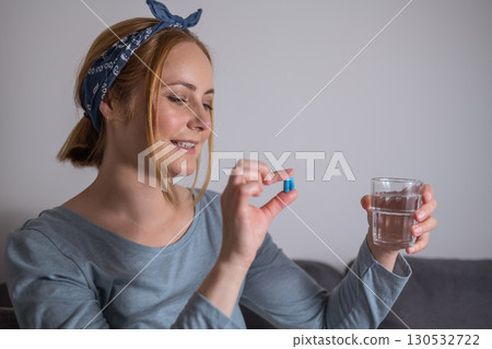 Middle age woman holding blue pills with fingers. Health care, dietary supplements, treatment of depression and diseases Middle age woman holding blue pills with fingers. Health care, dietary supplements, treatment of depression and diseases 130532722