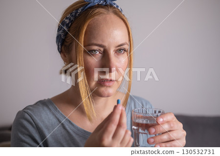 Middle age woman holding blue pills with fingers. Health care, dietary supplements, treatment of depression and diseases Middle age woman holding blue pills with fingers. Health care, dietary supplements, treatment of depression and diseases 130532731