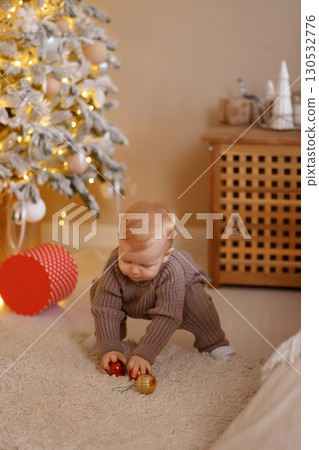 Little baby decorating Christmas tree in cozy room with carpet and warm lights Little baby decorating Christmas tree in cozy room with carpet and warm lights 130532776