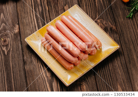 Pile of raw sausages stacked on a ceramic plate, ready for cooking, close-up view Pile of raw sausages stacked on a ceramic plate, ready for cooking, close-up view 130533434
