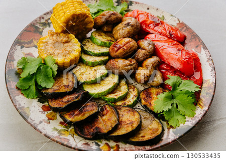 Grilled vegetables with herbs on ceramic plate. Colorful healthy vegan meal top view 130533435