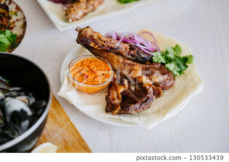 Grilled lamb ribs with red onion, herbs and spicy sauce on lavash flatbread Grilled lamb ribs with red onion, herbs and spicy sauce on lavash flatbread 130533439