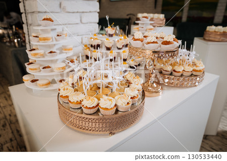Luxurious wedding dessert table with cupcakes, macarons, and creamy mini treats 130533440