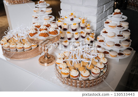 Luxury candy bar with cupcakes, macarons, and desserts on elegant golden trays Luxury candy bar with cupcakes, macarons, and desserts on elegant golden trays 130533443