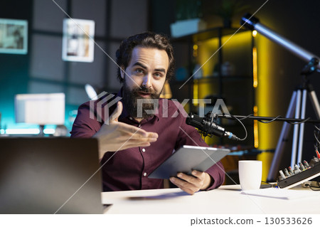 Portrait of content creator analyzing newly released gaming tablet received from sponsor, doing influencer marketing. Media star reviewing digital device during sponsorship advertising 130533626
