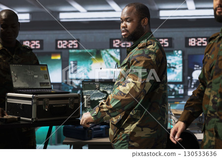 Counterintelligence team combating terrorism using detection system on notebook. Intelligence officers in base of operations protecting national borders by tracking terrorists entering country Counterintelligence team combating terrorism using detection system on notebook. Intelligence officers in base of operations protecting national borders by tracking terrorists entering country 130533636