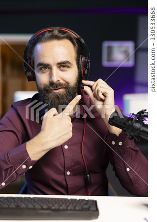 Audiophile reviewing newly launched gaming headphones, testing sound clarity on microphone. Technology internet show host checking device mic, making sure voice is captured loud enough 130533668