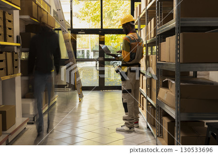 Blurred figures represent workers moving quickly in a small scale warehouse, symbolizing the routine of inventory, cargo preparation and e-business dispatch within logistics operations. Blurred figures represent workers moving quickly in a small scale warehouse, symbolizing the routine of inventory, cargo preparation and e-business dispatch within logistics operations. 130533696