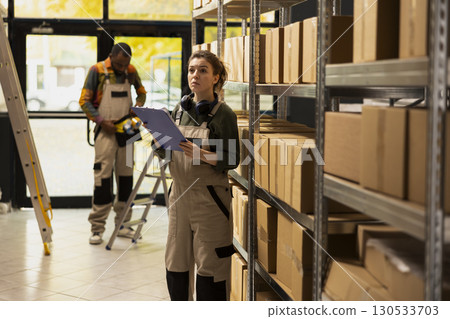 Female employee preparing products for dispatch in a small facility, ensuring quality control and shipment service efficiency for e-business and e-commerce delivery. Order processing. 130533703