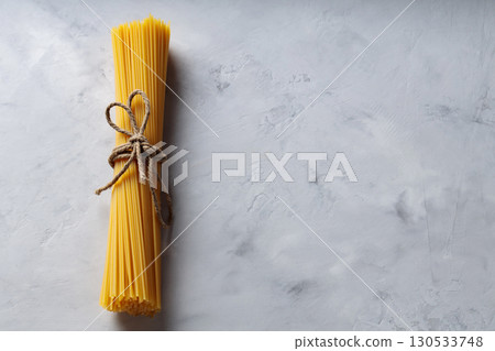 Uncooked Spaghetti Pasta with Natural Rope on Gray Background Top View Copy Space Uncooked Spaghetti Pasta with Natural Rope on Gray Background Top View Copy Space 130533748