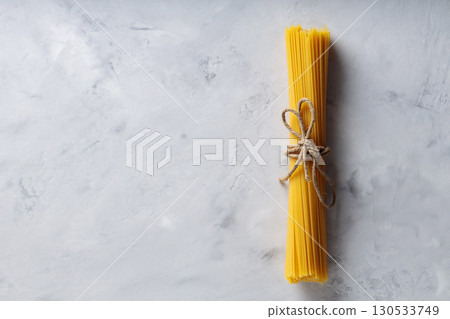 Uncooked Spaghetti Pasta with Natural Rope on Gray Background Top View Copy Space 130533749