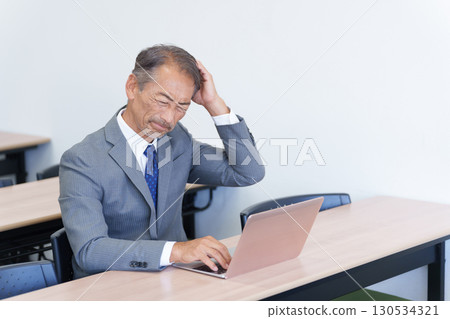 一位資深商人一邊看著電腦一邊思考 130534321