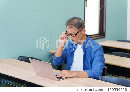 Senior man with presbyopia using a computer 130534328