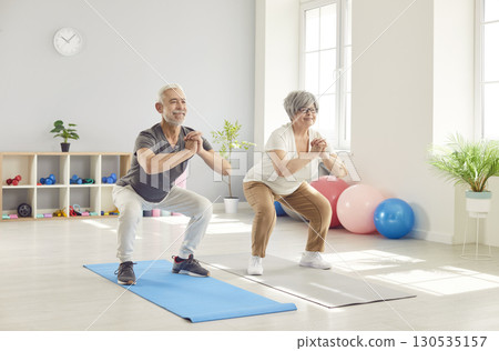 Active happy old senior doing squat morning exercise, sporty people practicing yoga lesson 130535157