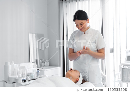 Beautician preparing for facial massage with woman 130535208