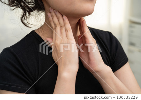 Asian woman touching her neck and throat for thyroid gland problem. Asian woman touching her neck and throat for thyroid gland problem. 130535229