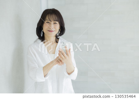 拿著智能手機的微笑的婦女 拿著智能手機的微笑的婦女 130535464